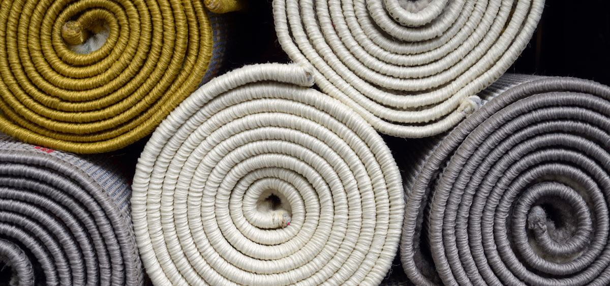 Rolls of domestic carpets in various colours